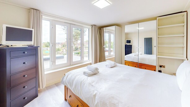 Habitación de hotel con cama, cómoda, televisor y ventana grande.
