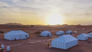 A desert landscape with multiple blue tents and a few white buildings. - Luna Luxury Camp (Rissani)