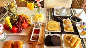 A breakfast spread with fruits, bread, pastries, and beverages on a table. - Luna Luxury Camp (Rissani)