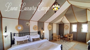 A luxurious tented accommodation with a large bed, multiple seating areas, and decorative wall elements. - Luna Luxury Camp (Rissani)
