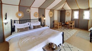 A luxurious tented accommodation with a large bed, multiple seating areas, and decorative wall elements. - Luna Luxury Camp (Rissani)