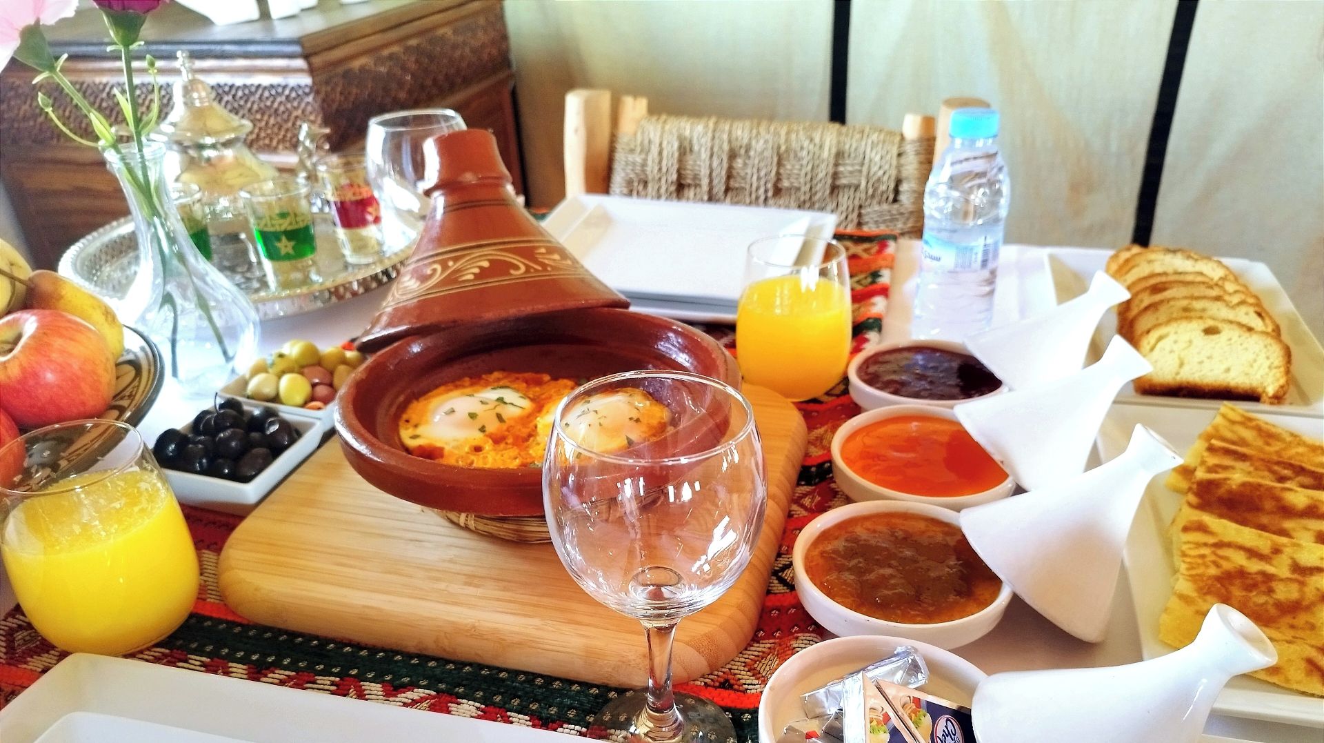 A breakfast table with a variety of dishes, including eggs, bread, and fruit.