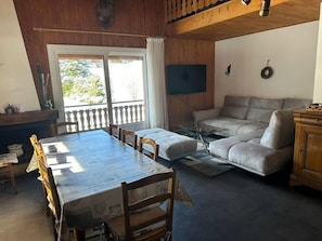 Um quarto com uma mesa de jantar, cadeiras, um sofá e uma televisão.
