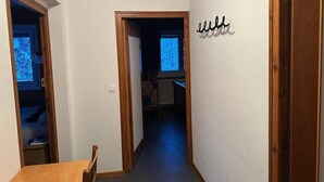 A hallway with a wooden door on the right, a small table, and a radiator in the background.