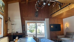 A cozy cabin interior with a dining area, sofa, and a mounted animal head.