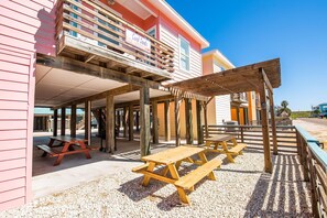 A beachside building with a covered patio area, picnic tables, and a sign reading "Coral Sands." - Sandy Coral (Port Aransas)