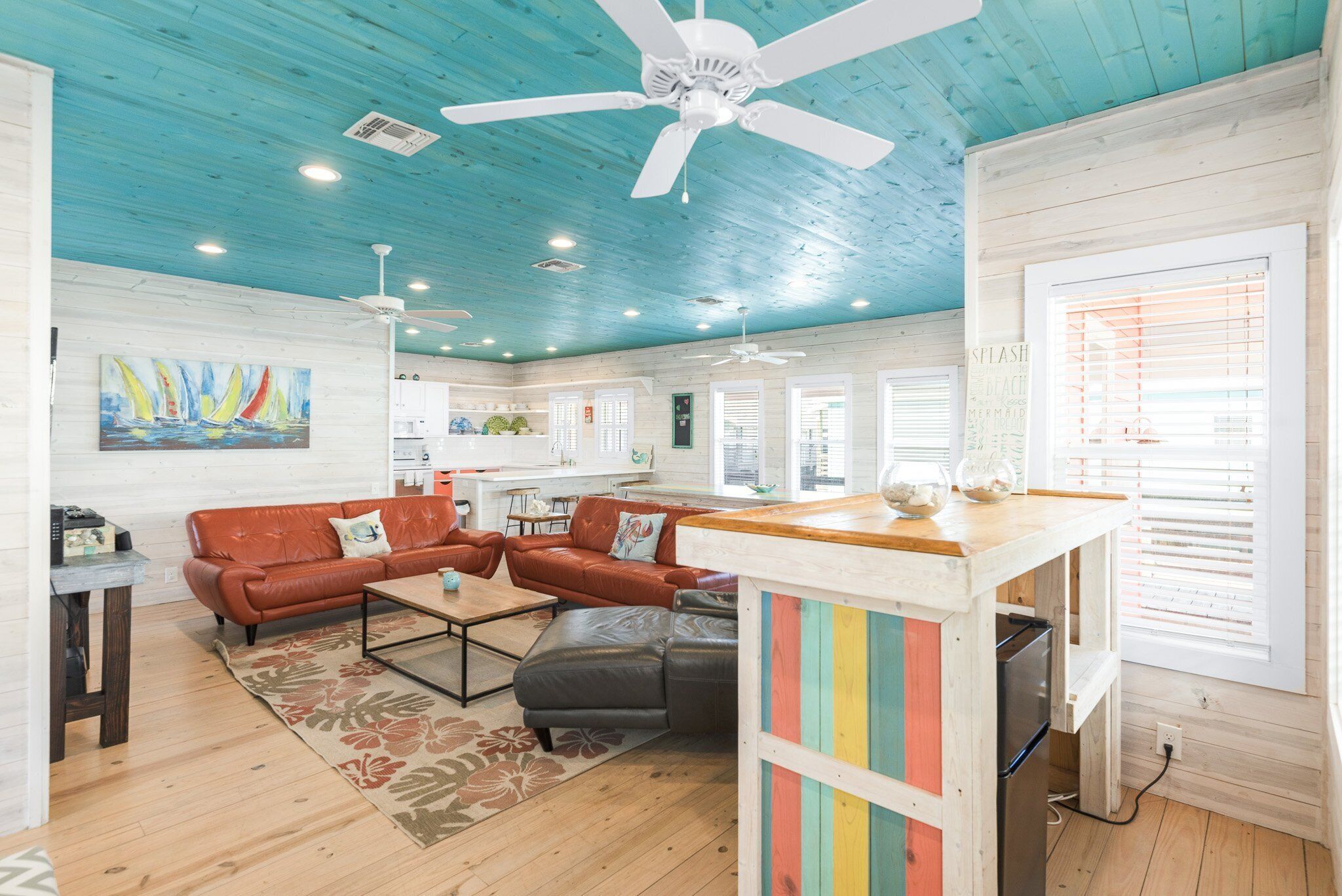A spacious living area with a wooden ceiling, a dining table, and a kitchen in the background.