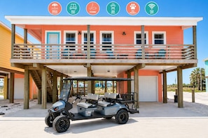 Een meerhoog gebouw met een overdekt terras, een golfkar en pictogrammen voor voorzieningen zoals toegang tot het strand, golfkar huren, vismogelijkheid, barbecuegrill, huisdiervriendelijk en gratis WiFi.