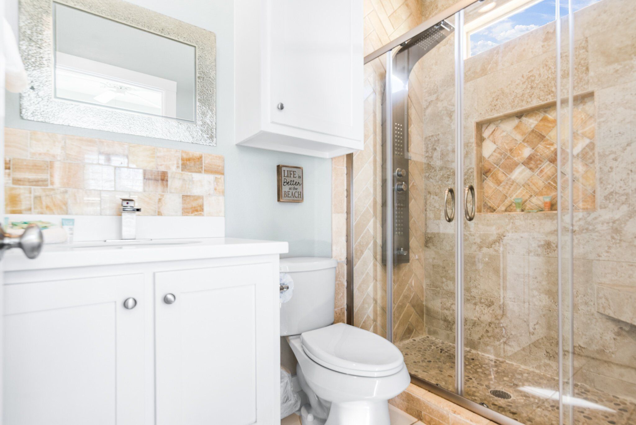 Une salle de bain avec des toilettes blanches, une douche en verre et un mur recouvert de carreaux.