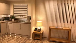 A modern kitchen with a built-in microwave, a sink, and a wooden table with a lamp. - ExploreNESS Apartment  (Inverness)