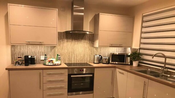 A modern kitchen with a built-in oven, microwave, and stainless steel appliances. - ExploreNESS Apartment  (Inverness)