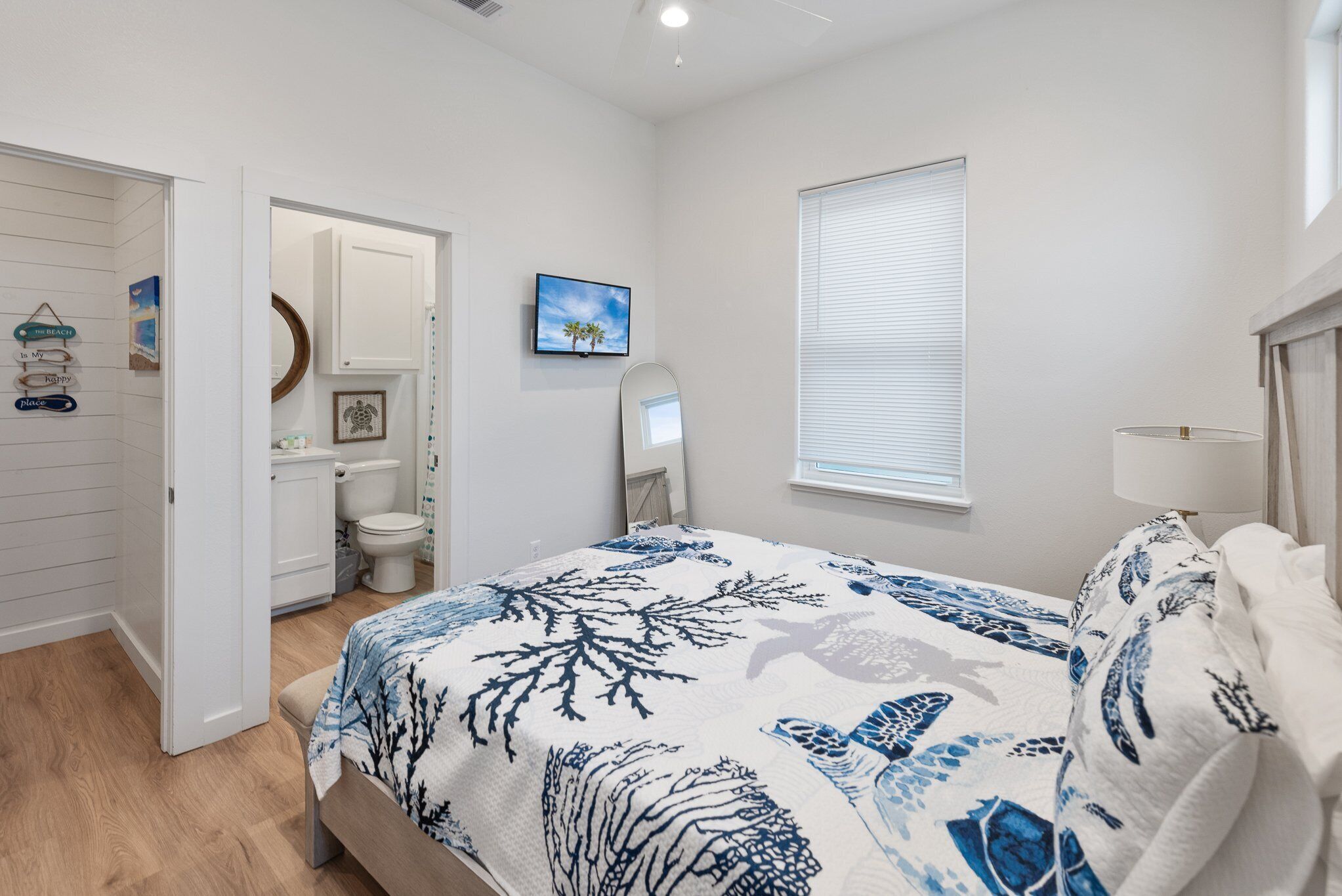 A bedroom with a bed, a bathroom with a toilet, a mirror, and a window.