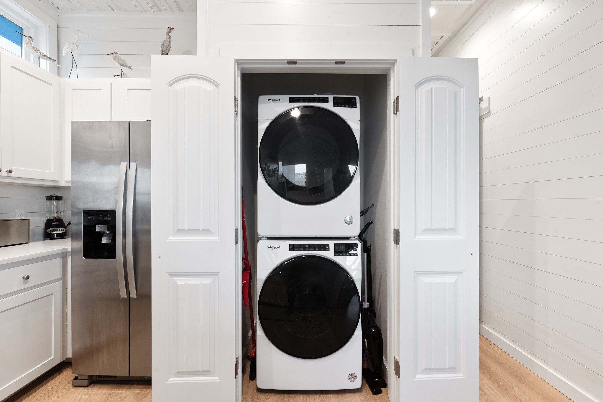A compact kitchen with a stainless steel refrigerator, a built-in washer and dryer, and white cabinetry.