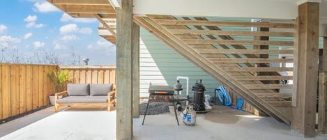A covered outdoor area with a pool, wooden deck, and a grill.