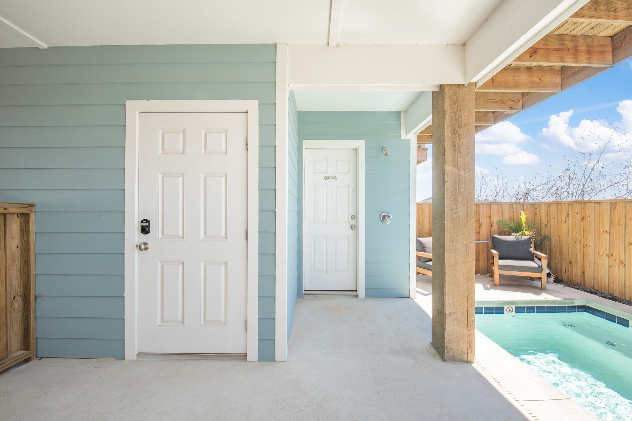 A house with a pool, a covered patio, and a door leading to the pool area.