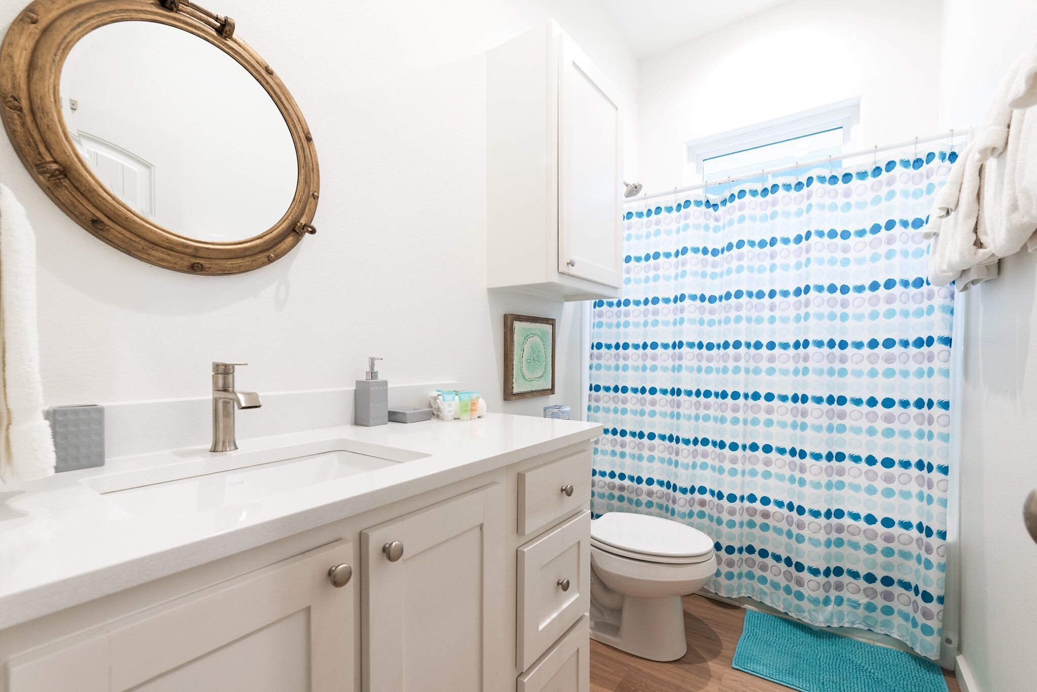 A bathroom with a white sink, a mirror, a toilet, and a shower curtain with a polka dot pattern.