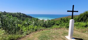 A cross on a grassy hill overlooking a beach. - Maison Familiale (Bidart)