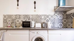 A kitchen with a washing machine, a toaster, and a kettle on the countertop. - Chambre Portal - Hypercentre - Gaillac (Gaillac)