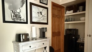 Une cuisine avec une console blanche, une horloge et des photographies encadrées accrochées au mur.