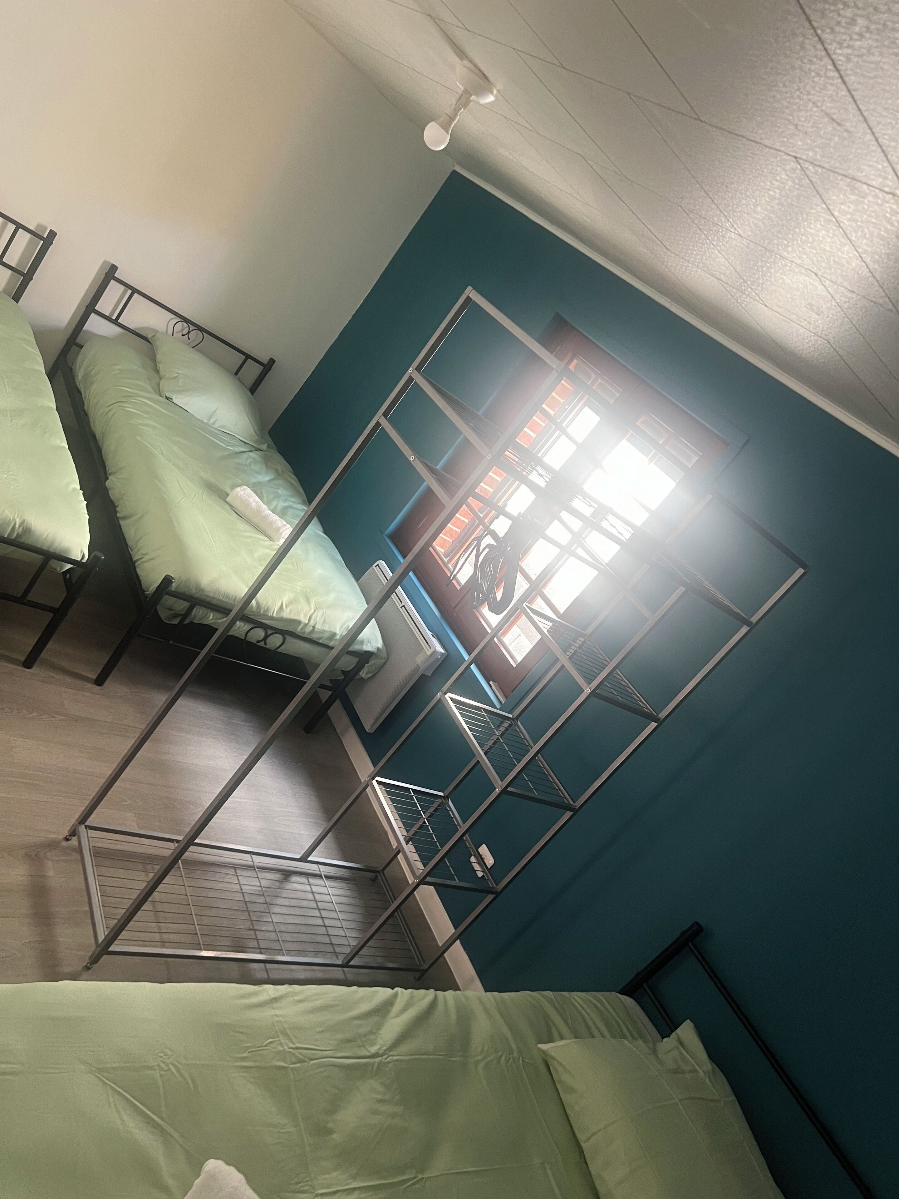 A dormitory room with bunk beds, a ceiling fan, and a window with blinds.