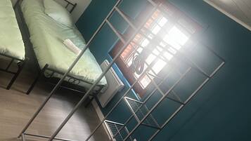 A dormitory room with bunk beds, a ceiling fan, and a window with blinds.