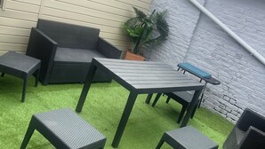 Un espace patio avec une table et des chaises, une plante en pot et un mur en briques.