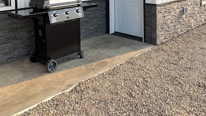 A house with a barbecue grill in front, number 10309 on the wall, and a door marked 2.