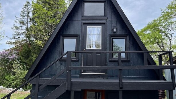 A black triangular cabin with a wooden door, a small porch, and a window. - Honest Abe Frame @ Sunrise (Ellicottville)