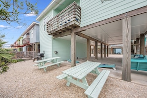 A covered outdoor area with picnic tables and a barbecue grill.