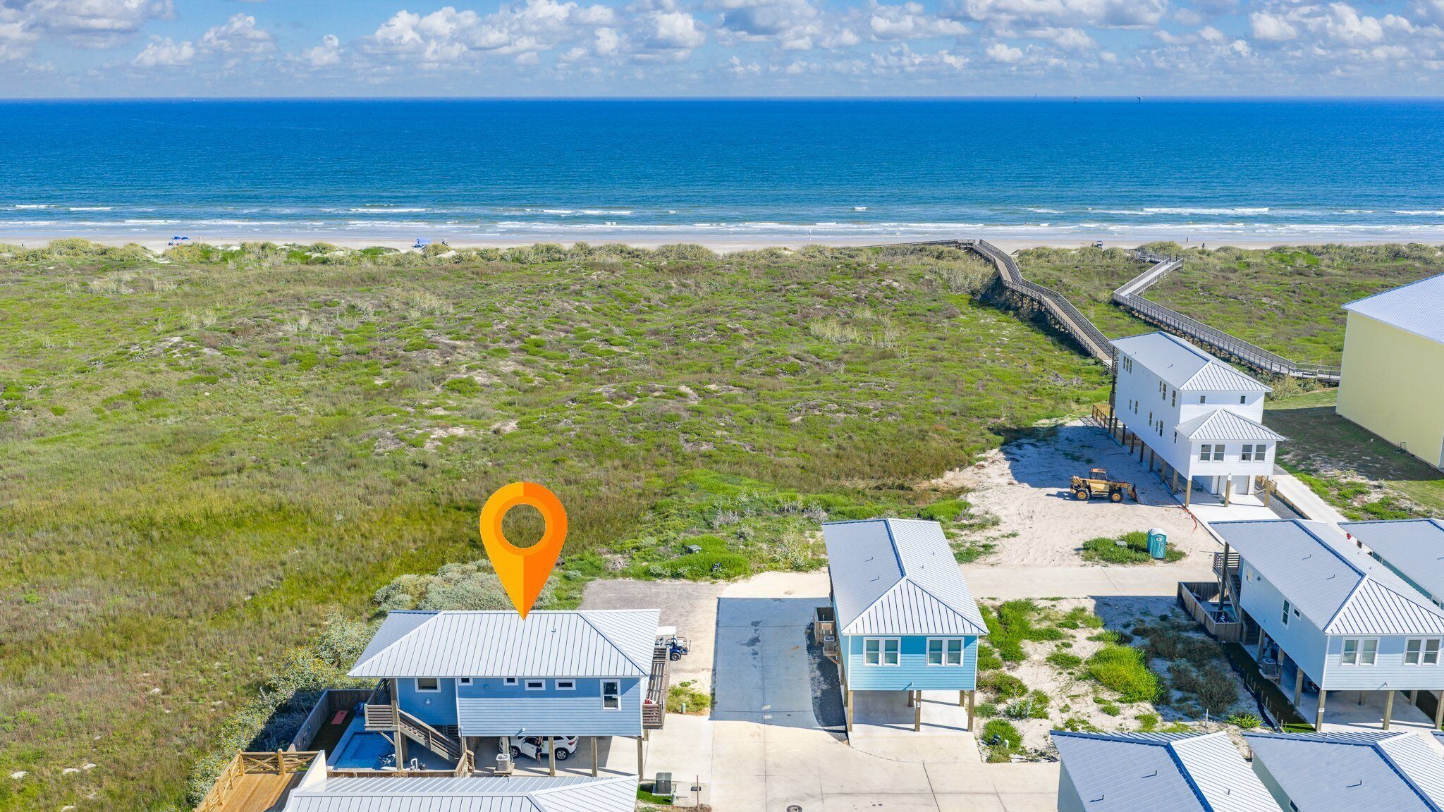 A coastal property with multiple buildings, a wooden boardwalk, and a view of the ocean.