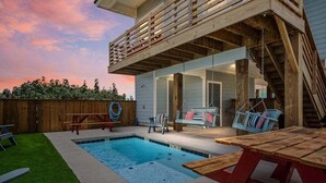 A backyard with a swimming pool, wooden deck, and outdoor seating. - Jetty Set Go! Ocean Views & Private Pool! (Port Aransas)