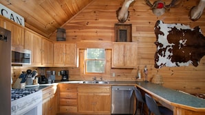 Una cocina estilo cabaña con armarios de madera, estufa, pileta y barra.