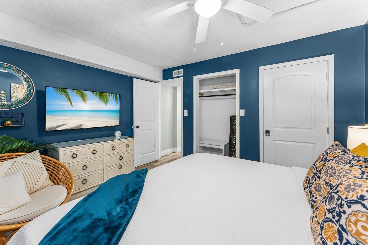 A bedroom with a bed, a dresser, a chair, a TV, and a closet.