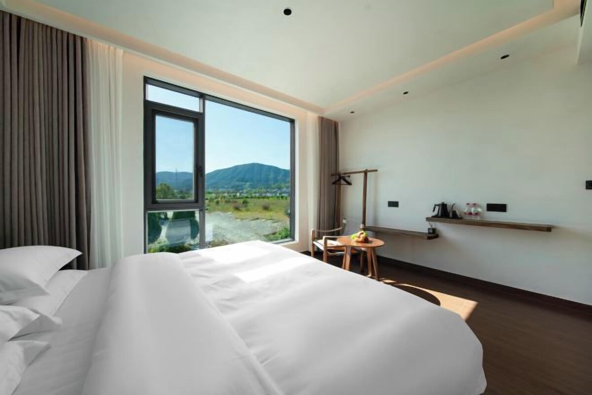 Ein Hotelzimmer mit einem großen Bett, einem Schreibtisch und Blick ins Freie.