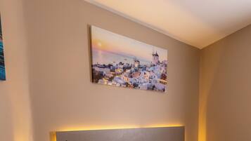 A neatly arranged bedroom with a bed, bedside table, and a wall-mounted painting.