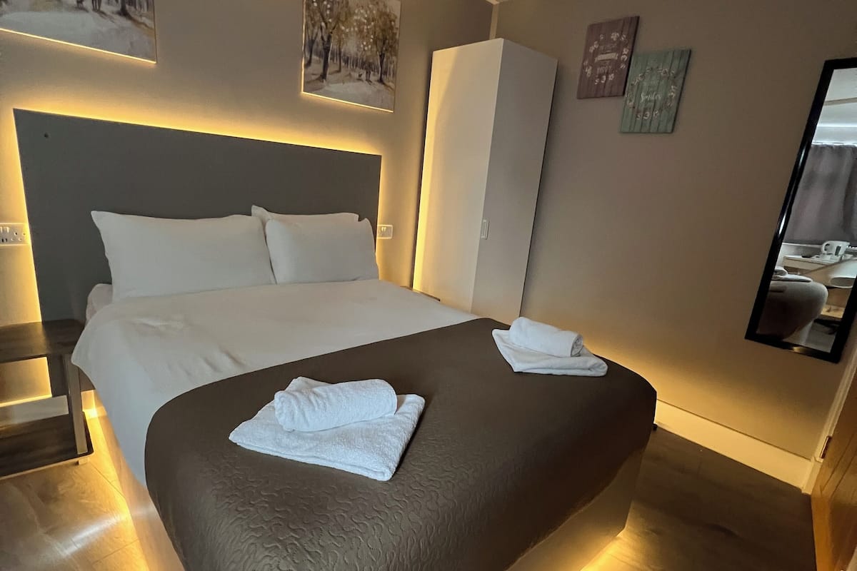 A modern hotel room with a large bed, a wardrobe, and a flat-screen TV.
