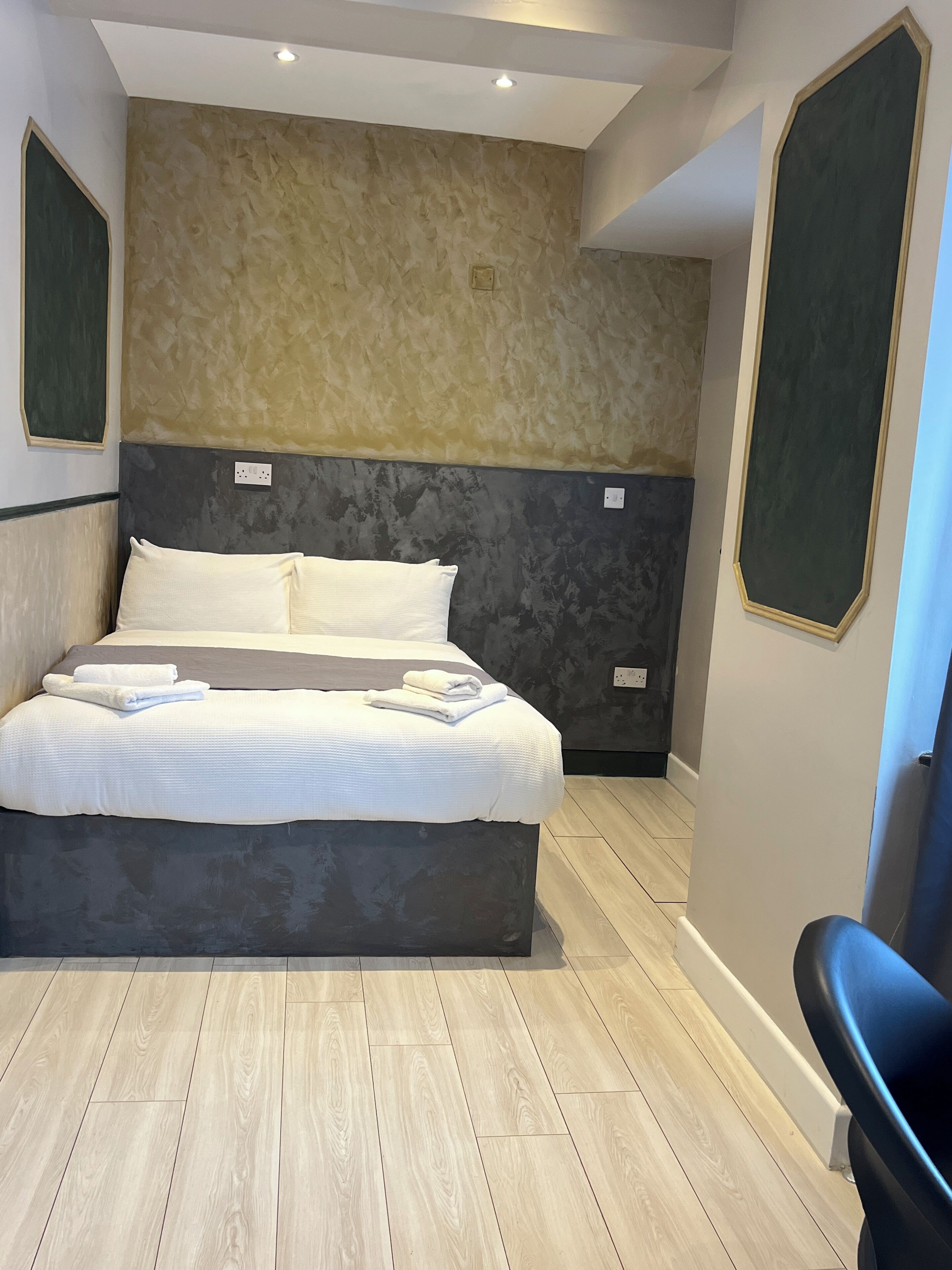 Ein modernes Schlafzimmer mit einem großen Bett, einem Kopfteil mit strukturierter Optik und Holzboden.