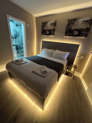 A modern bedroom with a large bed, a glass door leading to a balcony, and two wall-mounted artworks. - Rest Inn Edmonton (London)