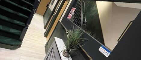 A hotel lobby with a staircase, a reception desk, and a plant.