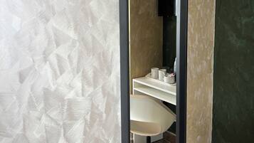 A bathroom with a white sink, a chair, and a black TV mounted on the wall.