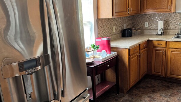 Una cocina con refrigerador de acero inoxidable, armarios de madera, un letrero de cafetería y un salpicadero de azulejos.