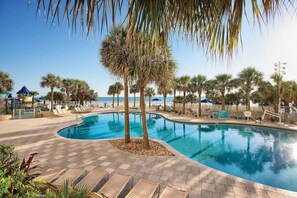 Relax by the pool surrounded by palm trees and lounge chairs.