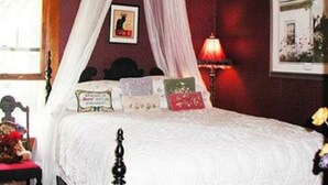 A bedroom with a four-poster bed, a nightstand, a lamp, and a framed picture on the wall. - Relax in our Parlor Room at The Cobblestone Bed & Breakfast (Birchwood)