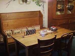 A wooden dining table with chairs, a bench, and a cabinet with glass doors.