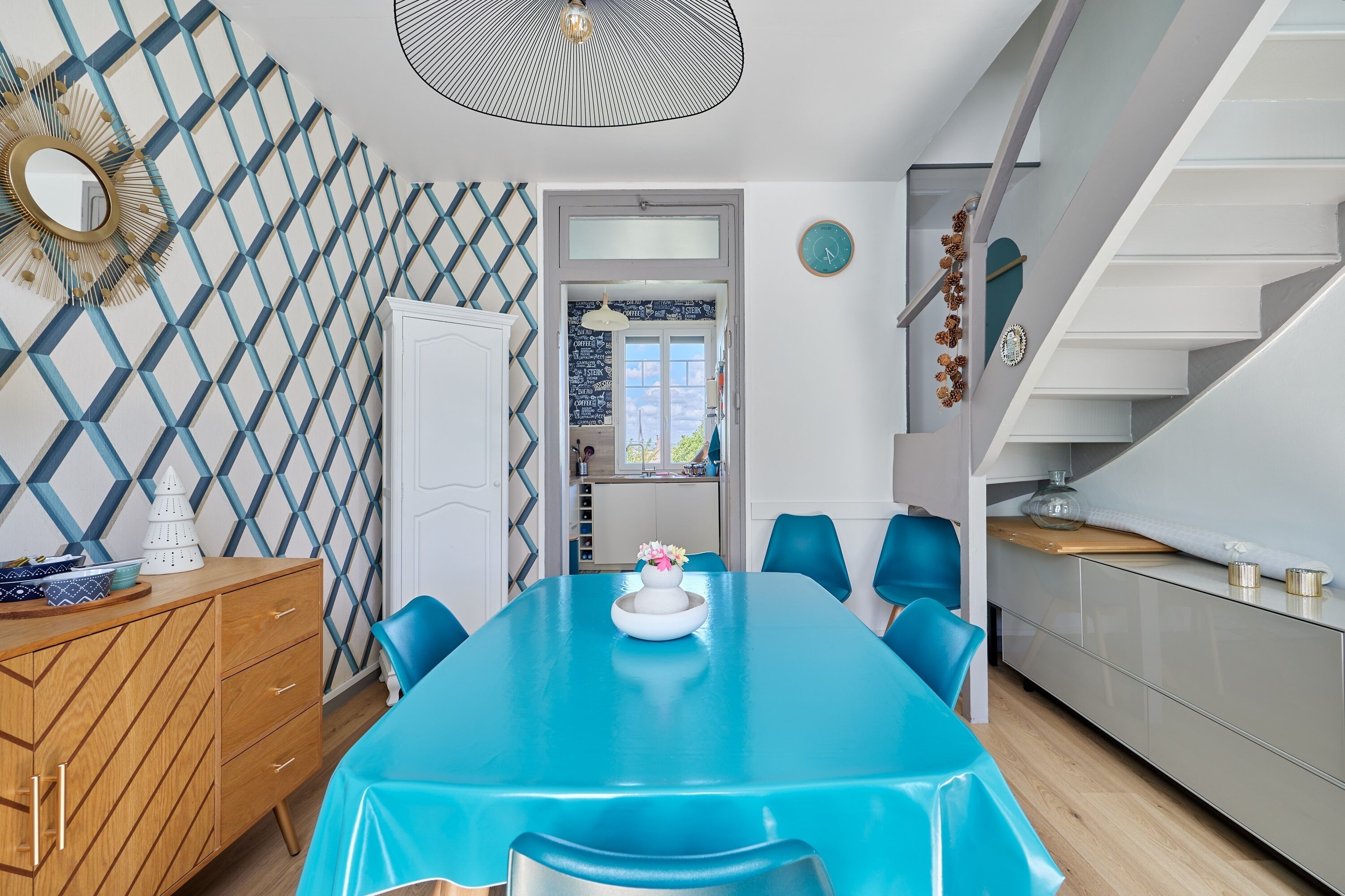 Un coin repas avec une table bleue, des chaises assorties et un buffet en bois.