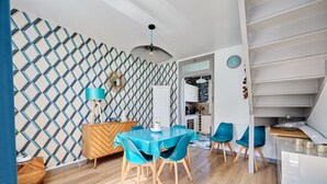 A modern kitchen with white cabinetry, a blue dining table with matching chairs, and a patterned wall. - La Halte Sainte-Catherine - Maison à 15min de la plage (Honfleur)