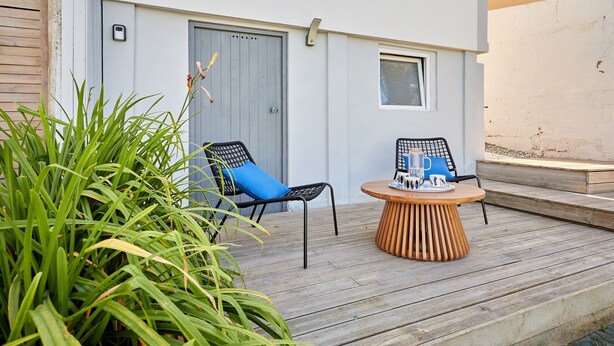 An outdoor seating area with two chairs and a table, surrounded by greenery. - La Halte Sainte-Catherine - Maison à 15min de la plage (Honfleur)