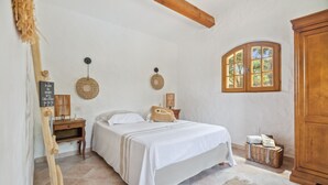 A bedroom with a bed, bedside tables, a wooden wardrobe, a window, and a wall-mounted lamp. - Chez Nous Baraille - Appt climatisé avec piscine (Puget-sur-Argens)