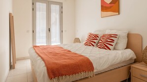 A bedroom with a bed, a nightstand, a lamp, and a door. - Le Cocon de la Pinède - Antibes, proche plage (Antibes)