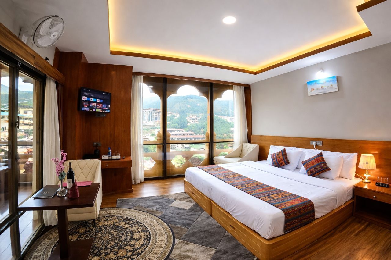 A hotel room with a large bed, a TV, a desk, a chair, and a view of the city.